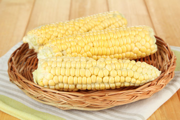 Fresh corn on wicker mat, on wooden background