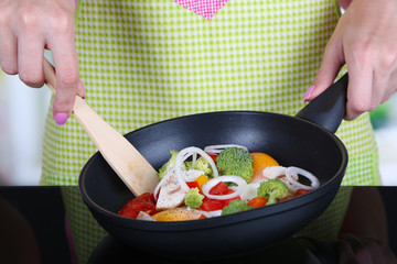 Hands cooking vegetable ragout in pan in kitchen
