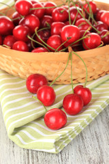 Cherry berries in wicker basket on wooden table close up