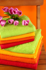 Towels and flowers on wooden chair on orange background