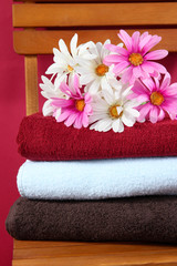 Obraz na płótnie Canvas Towels and flowers on wooden chair on brown background