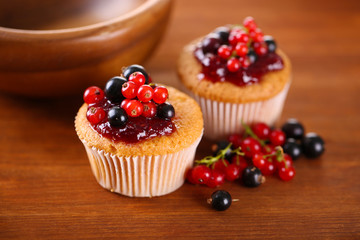 Tasty muffins with berries on wooden background