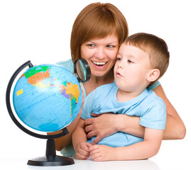 Mother is looking at globe with her son