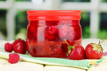 Home made berry jam on wooden table on window background