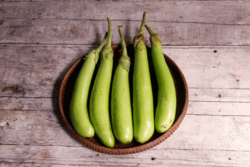 Long eggplants in the threshing basket on wooden table