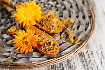 Fresh and dried calendula flowers on wooden background