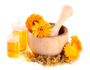 Medicine bottles and calendula flowers in wooden mortar