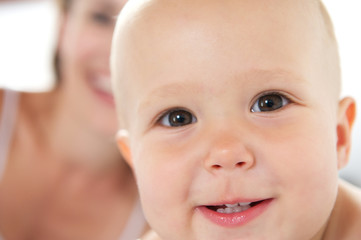 Baby smiling with mother in background