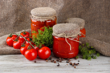 Tasty canned and fresh tomatoes on wooden table