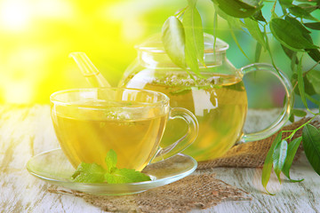 Teapot and cup of herbal tea with fresh mint flowers
