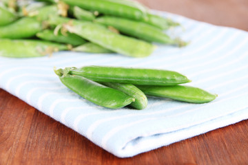 Green peas  on napkin on wooden table