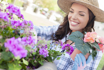 Cheery Young Adult Woman Wearing Hat Gardening Outdoors