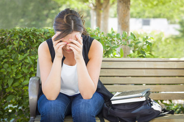 Depressed Young Woman Sitting Alone on Bench Next to Books