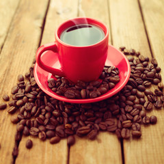 Red coffee cup with coffee beans on wooden background