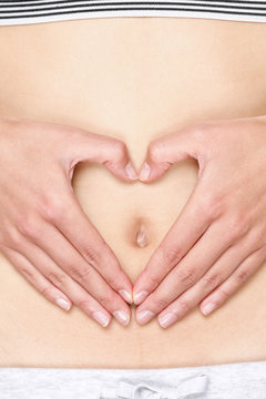 Hands forming heart on stomach - love your body concept