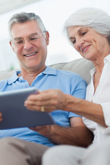 Couple using a digital tablet sitting on the couch