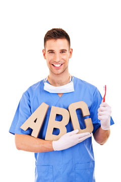 Portrait of happy male dentist with letters and toothbrush