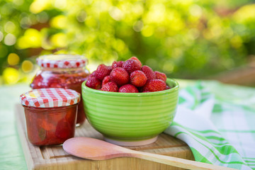 Homemade strawberry jam in different jars and fresh ripe strawbe