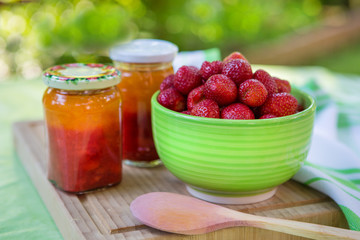 Homemade strawberry jam in different jars and fresh ripe strawbe