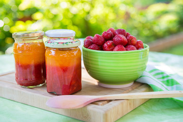 Homemade strawberry jam in different jars and fresh ripe strawbe