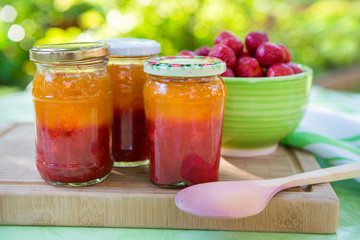 Homemade strawberry jam in different jars and fresh ripe strawbe