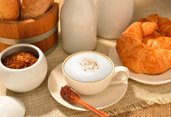A cup of cappuccino with bread and croissant