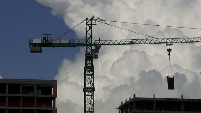A construction site with one crane on the cloudscape background
