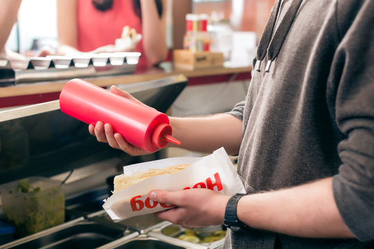 Hotdog being diligently prepared by fast food chef