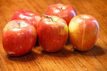Five Ripe Red Apples on a Wood Table