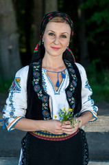 beautiful singer with flowers in her hands posing at countryside