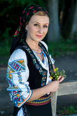 beautiful singer with flowers in her hands posing at countryside