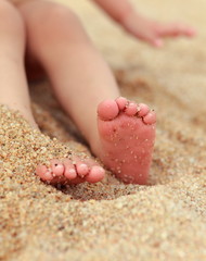Baby feet lying on yellow beach sand