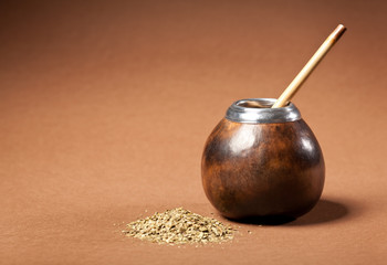 calabash and bombilla with yerba mate isolated on brown backgrou