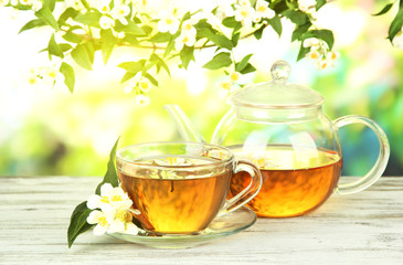 Cup of tea with jasmine, on wooden table, on bright background