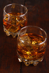 Brandy glasses with ice on wooden background
