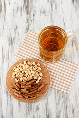 Beer in glass crunches, and nuts on napkin on wooden table