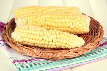 Fresh corn on wicker mat, on wooden background