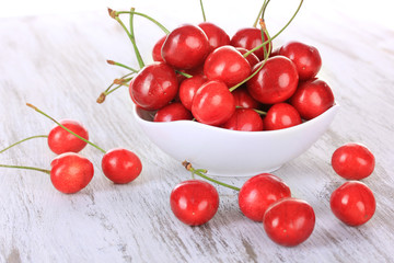 Cherry berries in bowl on wooden table close up
