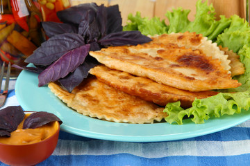 Tasty chebureks with fresh herbs on plate, close-up