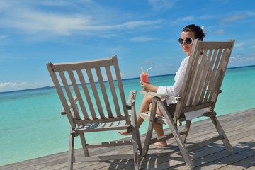 Beautiful young woman with a drink by the sea