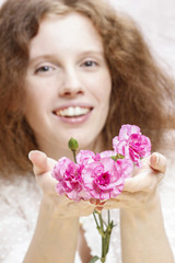 Young beautiful girl holding pink carnation flowers. Pretty smil