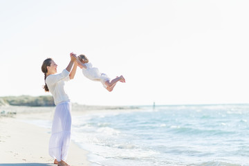 Happy mother and baby playing on beach