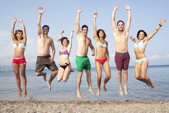 Sieben Personen springen am Strand
