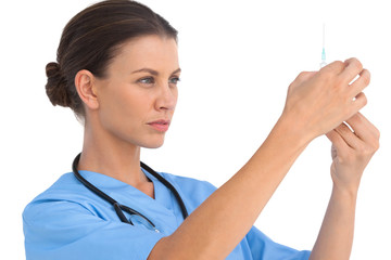 Serious surgeon holding up a syringe and checking it