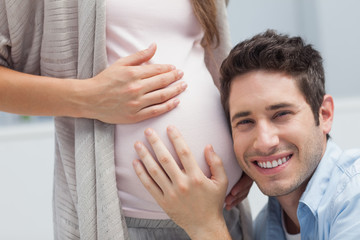 Fototapeta premium Man listening to the belly of his pregnant wife