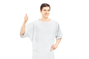 Smiling male patient wearing hospital gown and giving thumb up