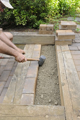 Worker Using Mallet to Align Bricks