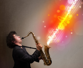 Young man playing on saxophone with colorful sound waves