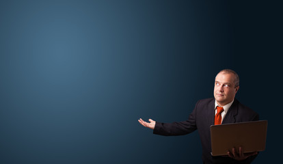 businessman holding a laptop and presenting copy space