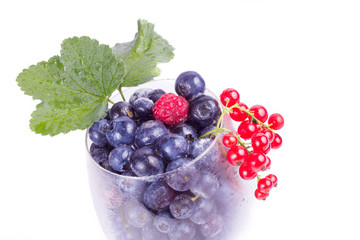 fresh and frozen berries in glass isolated on white